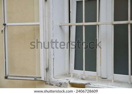 Old used window bars on house with damaged wall. Historic jailhouse with prison bars for maximum security. Institutionalized convict on cold winter.Traditional retro style windows. Shutters. Building.