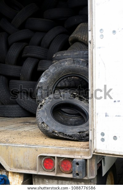 Old used worn tire tread waste tires of\
different sizes and treads from cars and trucks are stored inside\
an old semi trailer with an open door for processing, retreading,\
recycling or disposal
