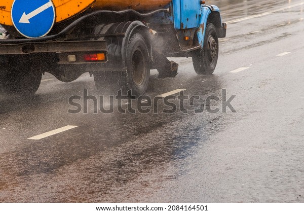 old utility truck moving on asphalt road under\
rainy day - close-up.
