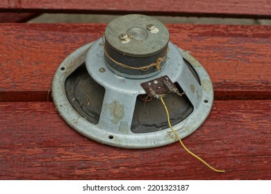 An Old Very Powerful Speaker With A Torn Diffuser And A Magnet From A Music Speaker In An Iron Base Lies On A Wooden Surface On The Street