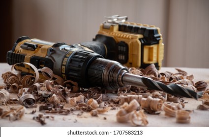 An Old Very Used Hand Drill Power Tool Lies On The Workbench With Wood Chips