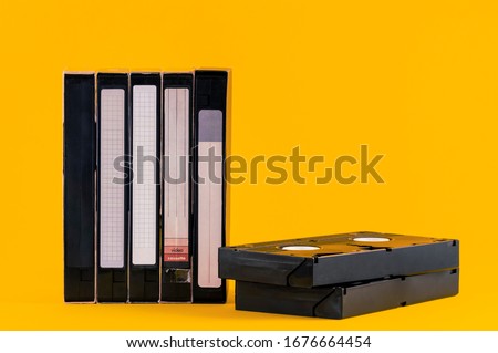 Old VHS video tapes isolated on yellow color background. Copy space for text. Old popular video technology from 1980s.