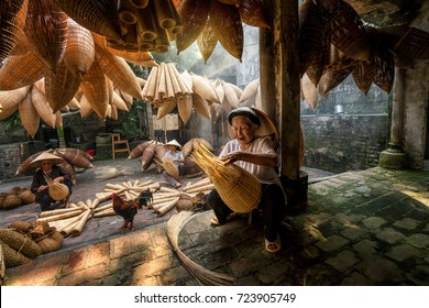 Old Vietnamese female craftsman making the traditional bamboo fish trap or weave at the old traditional house in Thu sy trade village, Hung Yen, Vietnam, traditional artist concept
