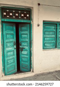 Old village house with open green textured door and windows showing the ancient Indian architecture.