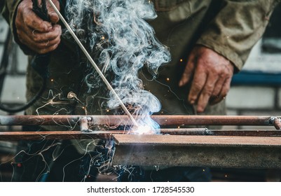 Old Village Welding Workshop. Elderly Man Working With Metal And Welding Electrode