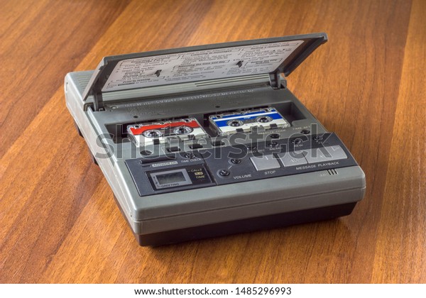 old vintage answering machine with two\
small tape cassettes on a wooden table\
surface