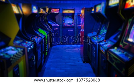 Old Vintage Arcade Video Games in an empty dark gaming room with blue light with glowing displays and beautiful retro design on a wide landscape photo