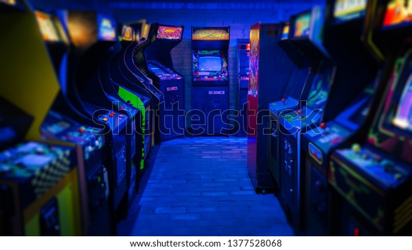 Old Vintage Arcade Video Games in an\
empty dark gaming room with blue light with glowing displays and\
beautiful retro design on a wide landscape\
photo