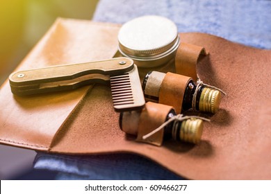 Old vintage barber shop tool on an old leather barber's purse. Vintage wooden beard comb and beard oils.