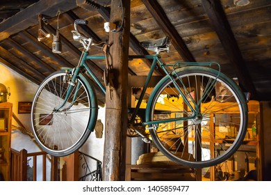 Old Vintage Bicycle Hanging On A Wooden Column In The Storage Room