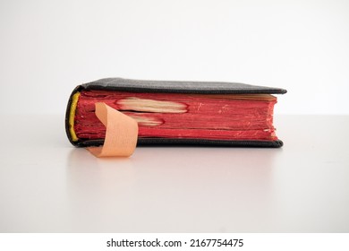 Old Vintage Black Closed Hardcover Book With A Satin Bookmark. Close Up Shot, Shallow Depth Of Field, White Background, No People