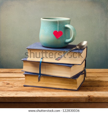 Old vintage books and cup with heart shape on wooden table