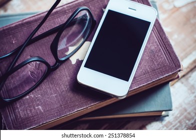 Old vintage books, smartphone and glasses on a wooden table - Powered by Shutterstock