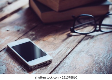 Old vintage books, smartphone and glasses on a wooden table - Powered by Shutterstock