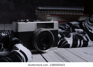 Old vintage camera on a rustic table against a black  background and low light 