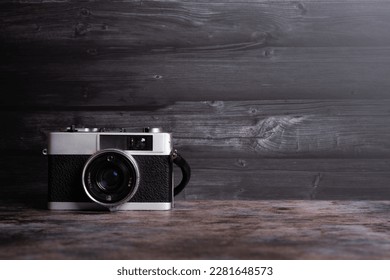 Old vintage camera  on a rustic table against a low light dark background - low light under exposed photography - Powered by Shutterstock