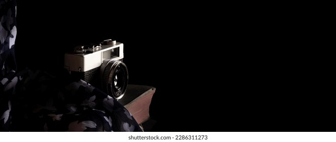 Old vintage camera  on a rustic table against a low light dark background - low light under exposed photography - selective focus - Powered by Shutterstock