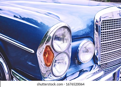 Old vintage car in blue with grille and lamps with lots of chrome