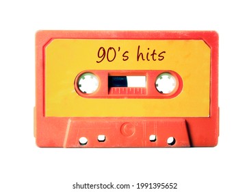 An old vintage cassette tape (obsolete music technology) with the handwritten text: 90's hits. Light red plastic body, vivid orange label, isolated on white.
				