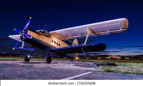 Old vintage classic airplane on small airfield in night time with clear sky. Abandoned biplane in long exposure under the stars
