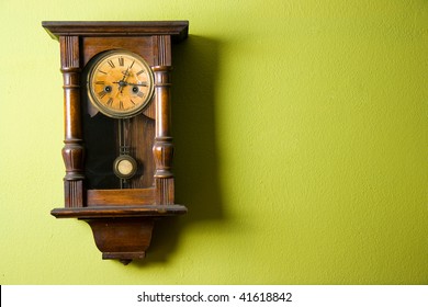 Old vintage clock hanging on green wall