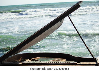 Old vintage decayed piano with a green ocean background, beach side