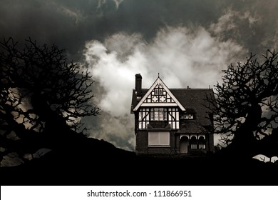 An Old Vintage Eerie Haunted House With Creepy Gnarly Dead Trees Against A Apocalyptic Dark Sky For Halloween Concept.