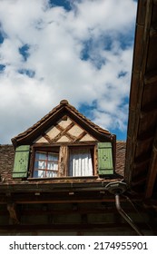 Old Vintage European Decorated Attic Windows With Open Wooden Shutter And Facade Decoration In A Small Village In Switzerland. Cloudy Blue Sky In The Background, No People.