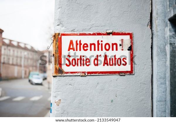 Old\
vintage inscription on wall building - Attention, sortie d\'autos -\
translated as pay attention, car exits from\
building