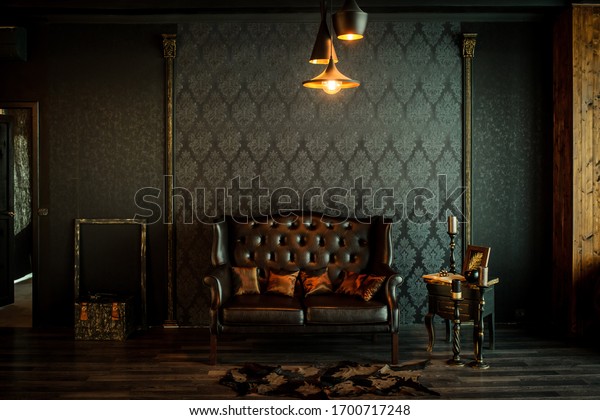 Old vintage interior with leather sofa, wood table\
and ceiling light.