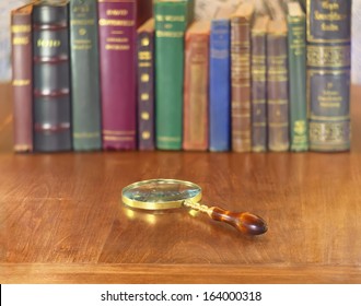 old vintage magnifying glass on wooden table with books row - Powered by Shutterstock