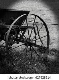 An Old Vintage Manual Plough Wheel Sitting In A Field In Black And White With A Vignetted Edge