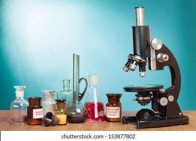 Old Vintage Microscope And Laboratory Glass Bottles On Table For Science Background