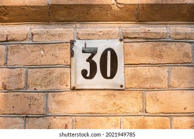 Old Vintage Minimalist Street Adress Number Sign With Number 30 On The Facade Of The Brick House Wall.