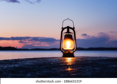 An old vintage oil lantern on a rock by the sea. Beautiful sunset sky and sea on background. Chill out travel concept.