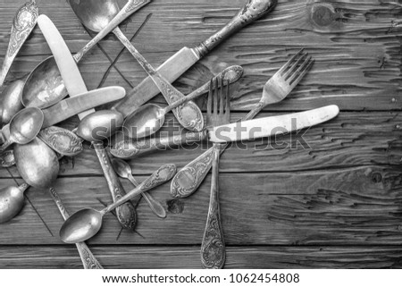 Old vintage ornamented cutlery on a wooden table. black and white photo
