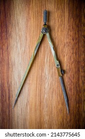 Old vintage pair of compasses on a wooden table background