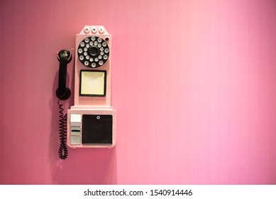 Old Vintage Phone Hanging On A Pink Wall With Copy Space