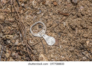 Old Vintage Pull Tab From A Soda Or Beer Can Laying Upside Down On The Beach At The Lake Polluting The Environment On A Bright Sunny Day In Springtime