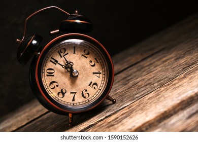 An Old, Vintage, Retro Alarm Clock On A Wooden Table Rolls Off A Slanted Table.