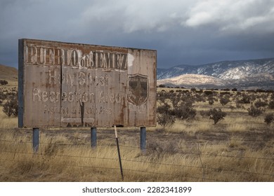 Old vintage roadside sign for a small town deep in the high desert of rural New Mexico with overcast sky - Powered by Shutterstock