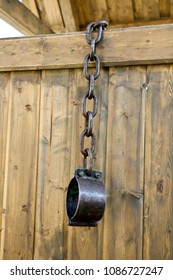 Old Vintage Rusty Iron Medieval Chains Or Shackles, Used For Locking Up Prisoners Or Slaves Between 1600 And 1800, On A Barns Wooden, Background. Shackles Of Slaves, Place Of The Execution Of Heretics