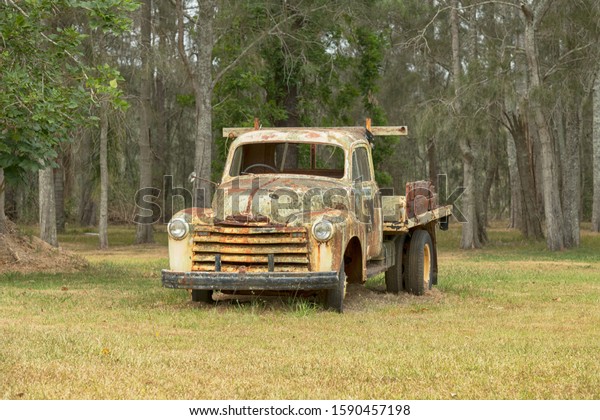 Old vintage rusty truck in a field\
on the edge of a forest in Central Coast, NSW,\
Australia.