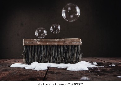 Old Vintage Scrub Brush With Bubbles And Soap On A Wooden Floor