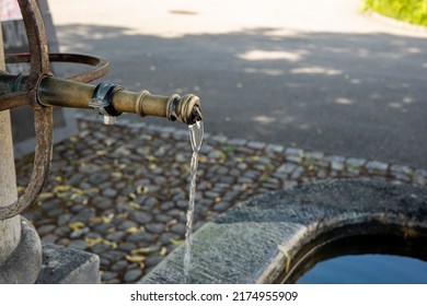 Old Vintage Stone And Forged Steel Public Drinking Water Fountain In A Small Village In Switzerland, Europe. Clear Pouring Water From The Faucet, Close Up Shot, No People.