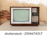 Old vintage television with blank screen. Old television on table in front of old wall background. Classic old obsolete TV.