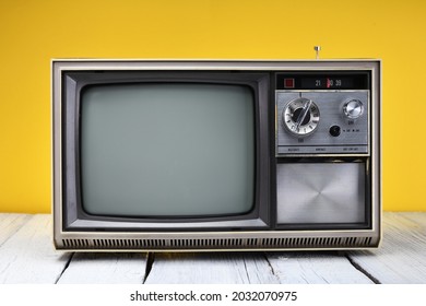 An Old Vintage Television Set From The 1970s Stands On A Wooden Table Against A Yellow Background. Vintage TVs 1980s 1990s 2000s.