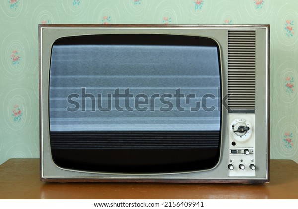 Old vintage TV with
screen noise in a room with vintage wallpaper. Interior in the
style of the 1960s.