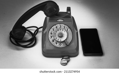 Old Vintage Wheel Phone With Telephone Tokens And Smartphone. Old And New In Comparison