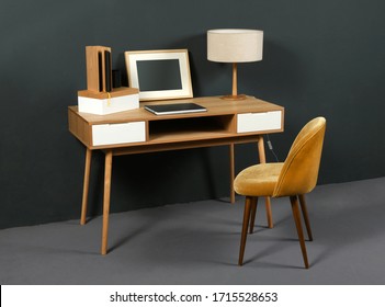 Old vintage wooden desk with retro table lamp, picture frame and easy chair in a room interior with grey decor - Shutterstock ID 1715528653